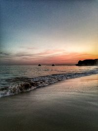 Scenic view of beach against clear sky during sunset