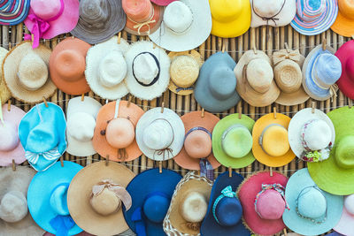 A variety of fashionable and colorful hats hanging on the bamboo backdrop of curbside shop.