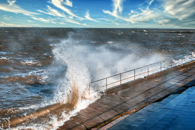 Sea waves splashing in swimming pool against sky