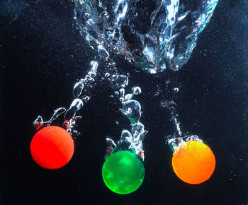 Close-up of multi colored splashing water against black background