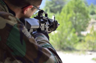 Man shooting with gun while standing outdoors