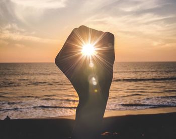 Optical illusion of hand holding sun at beach