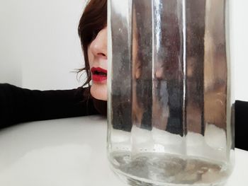 Close-up portrait of woman with reflection in glass