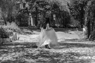 Rear view of woman standing against trees in forest