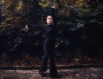 Portrait of young woman dancing against plants