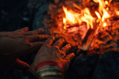 Cropped hands of person by bonfire at night