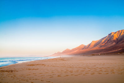 Scenic view of beach against clear sky during sunset