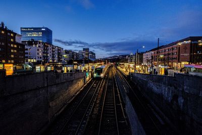 Railroad tracks in city against sky at night
