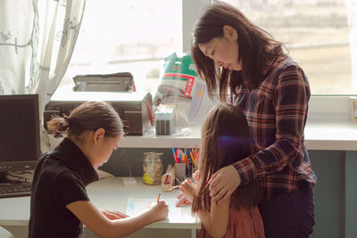 Mother and daughters draw together at home, authentic family life and candid lifestyle in apartment