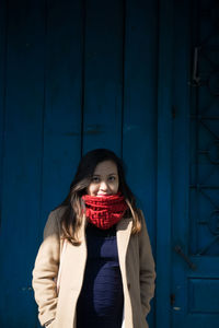 Portrait of young woman standing against wall