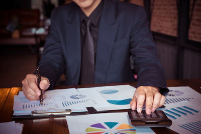 Midsection of man holding smart phone on table