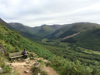 High angle view of man sitting on bench by mountains against sky at ben nevis