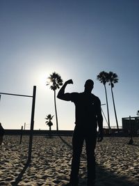 Silhouette man playing on beach against clear sky