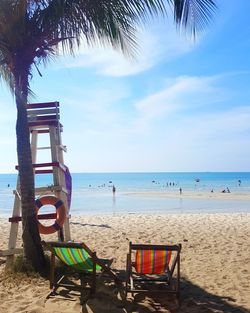 Man relaxing on chair at beach against sky
