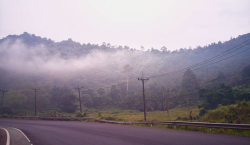 Road by trees against sky