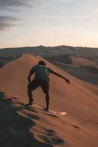 Full length of man on beach against sky during sunset