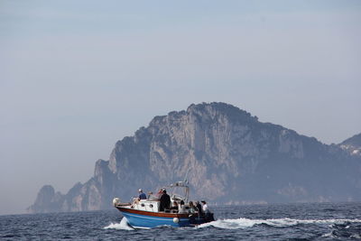 People on boat in sea against sky