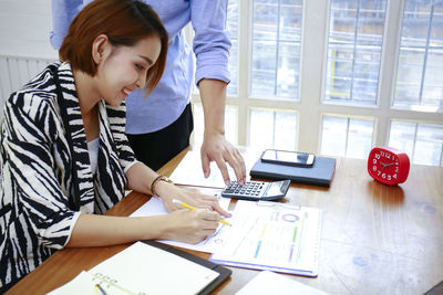 Young woman using mobile phone at table