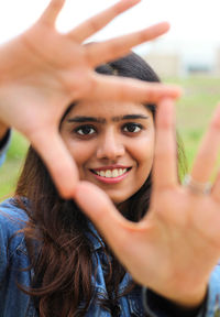 Portrait of smiling young woman seen through hands