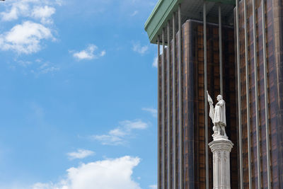 Low angle view of statue against sky and building