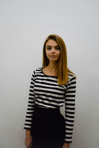 Portrait of young woman standing against white background