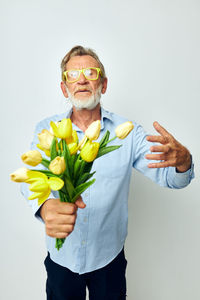 Midsection of woman holding flowers against white background