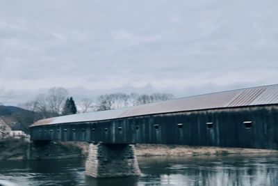 Built structure by river against sky