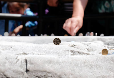 Close-up of coins on built structure by man in background