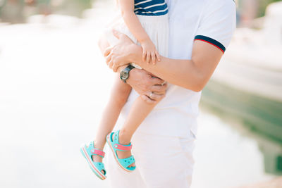 Midsection of child holding hands standing outdoors