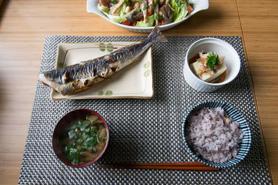 High angle view of fish in plate with rice and soup on table