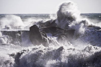 Man splashing water in swimming pool against sea