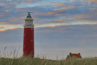 Lighthouse on field against sky during sunset