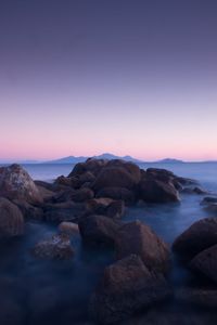 Rocks on beach against sky at sunset