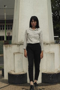 Portrait of woman standing against building