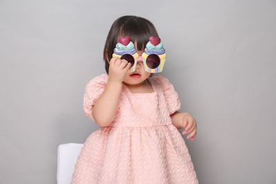 Young woman wearing sunglasses while standing against wall