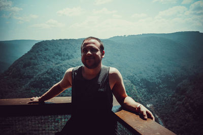 Portrait of young man in mountains against sky