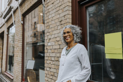 Portrait of young woman standing against building