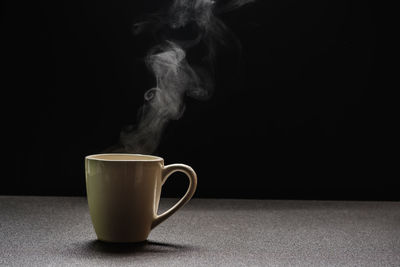 Close-up of coffee cup on table against black background