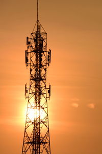 Low angle view of electricity pylon against sky during sunset