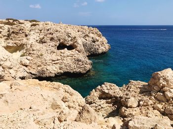 Scenic view of rocks in sea against blue sky