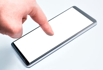 Close-up of hand holding mobile over white background