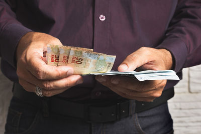 Midsection of man holding paper