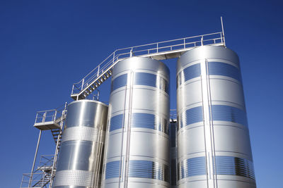 Low angle view of industry against clear blue sky