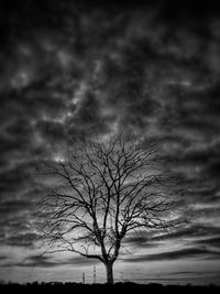 Low angle view of bare tree against cloudy sky