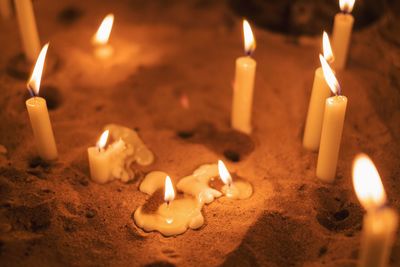 Close-up of lit candles in sand