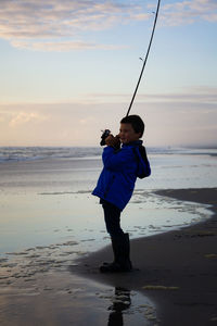 Full length of boy on beach against sky