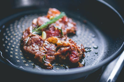 Beef steak with rosemary, garlic, salt and pepper inside iron skillet