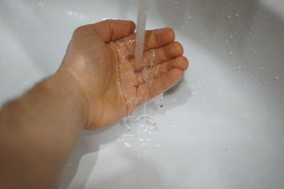 Close-up of hand touching water in bathroom