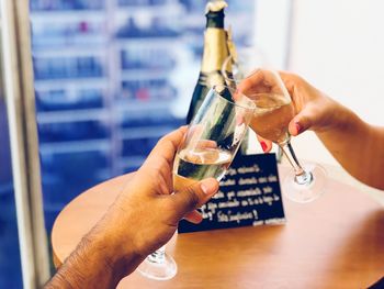 Cropped hands of friends toasting champagne flutes at table