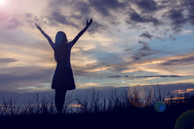 Silhouette woman standing on field against sky during sunset